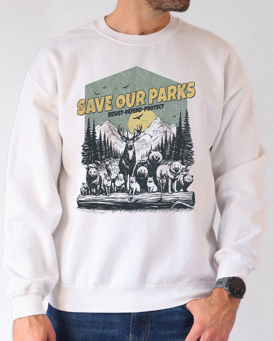 Man wearing a white sweatshirt with a retro wildlife design featuring animals lined up in a park and the quote 'Save Our Parks – Resist, Defend, Protect'.