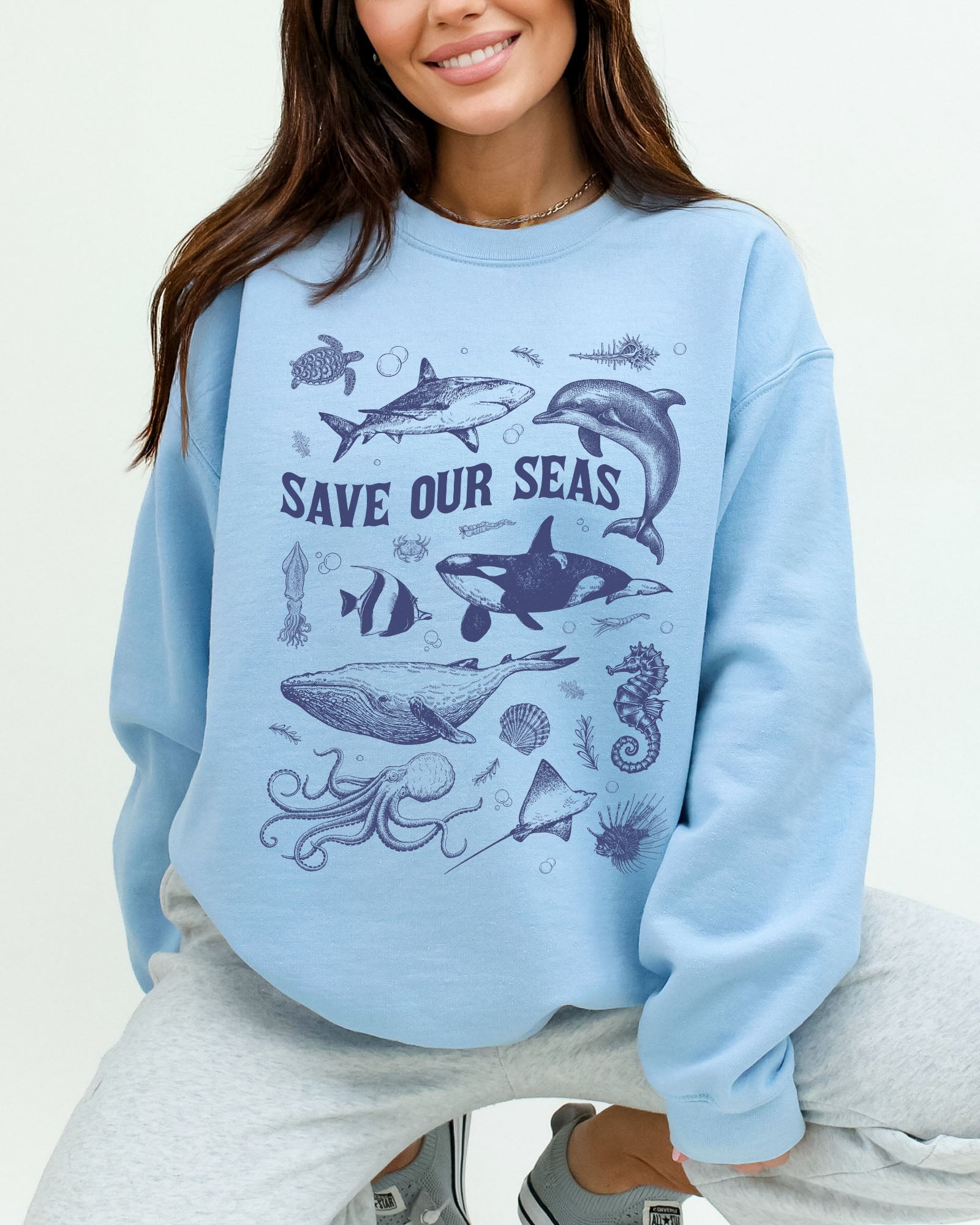 Model wearing light blue color sweatshirt with 'Save Our Seas' graphic design