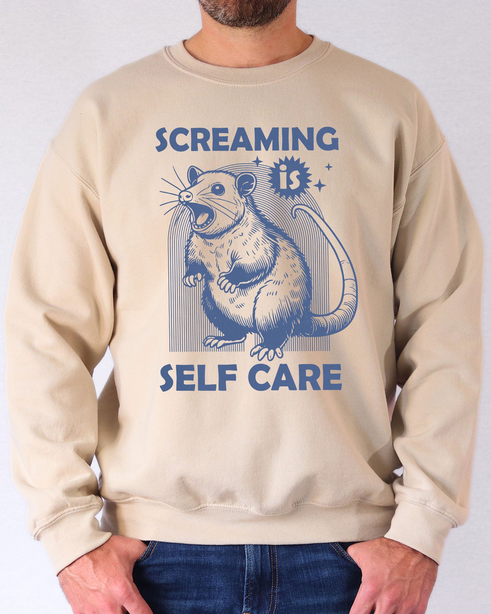 Model wearing sand color sweatshirt with 'Screaming Is Self Care' graphic design