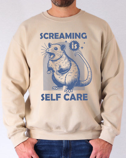 Model wearing sand color sweatshirt with 'Screaming Is Self Care' graphic design