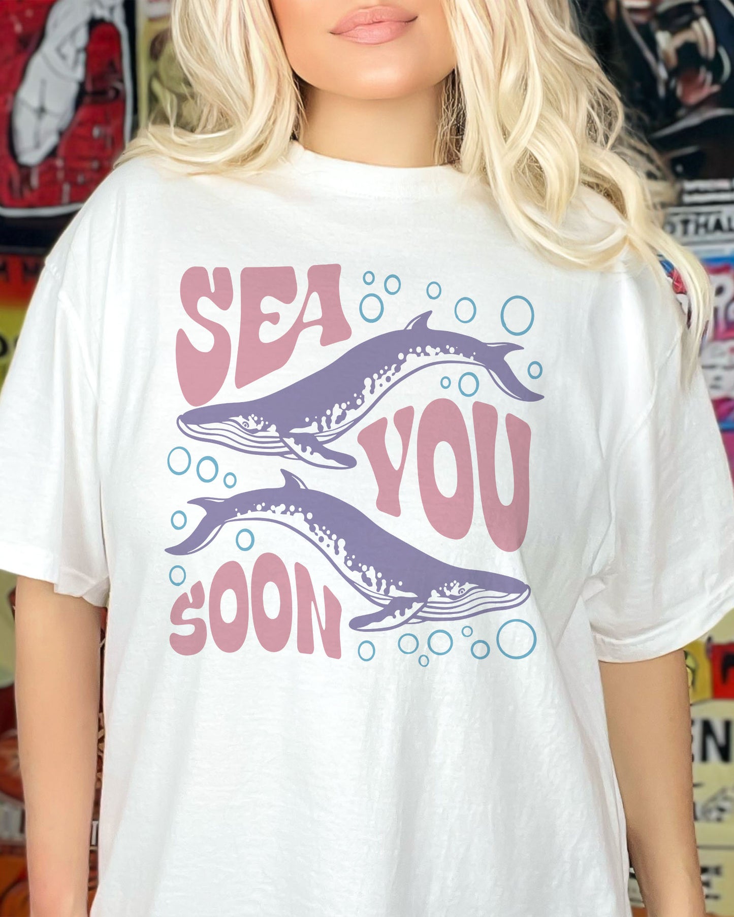 Woman wearing an oversized white 'Sea You Soon' t-shirt featuring a retro whales and sea life graphic.