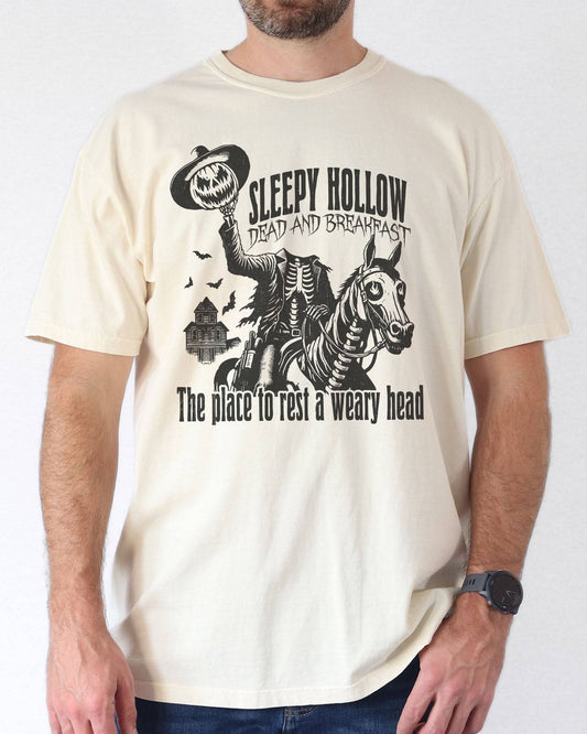 Model wearing ivory color shirt with 'Sleepy Hollow Dead And Breakfast - The Place To Rest A Weary Head' graphic design