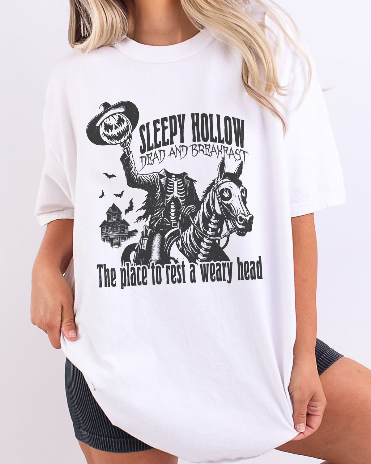 Model wearing white color shirt with 'Sleepy Hollow Dead And Breakfast - The Place To Rest A Weary Head' graphic design