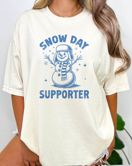 Woman wearing a funny Snow Day Support shirt in natural color with a retro snowman graphic