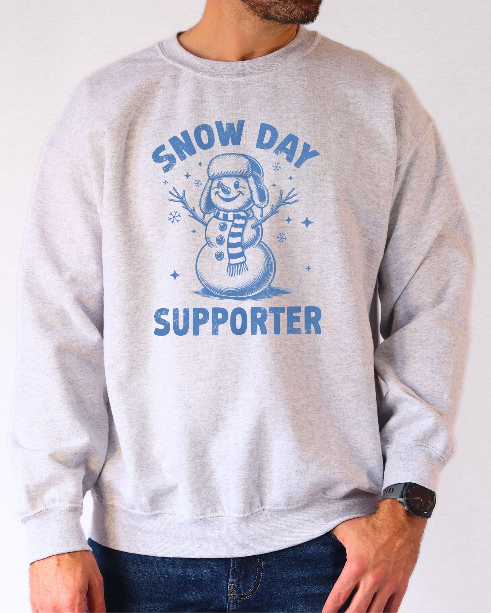Model wearing ash color sweatshirt with 'Snow Day Supporter' graphic design