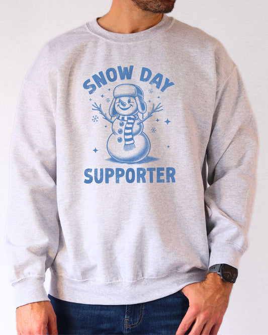 Model wearing ash color sweatshirt with 'Snow Day Supporter' graphic design