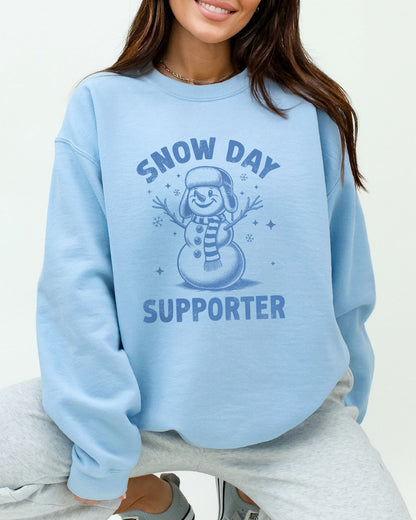 Model wearing light blue color sweatshirt with 'Snow Day Supporter' graphic design