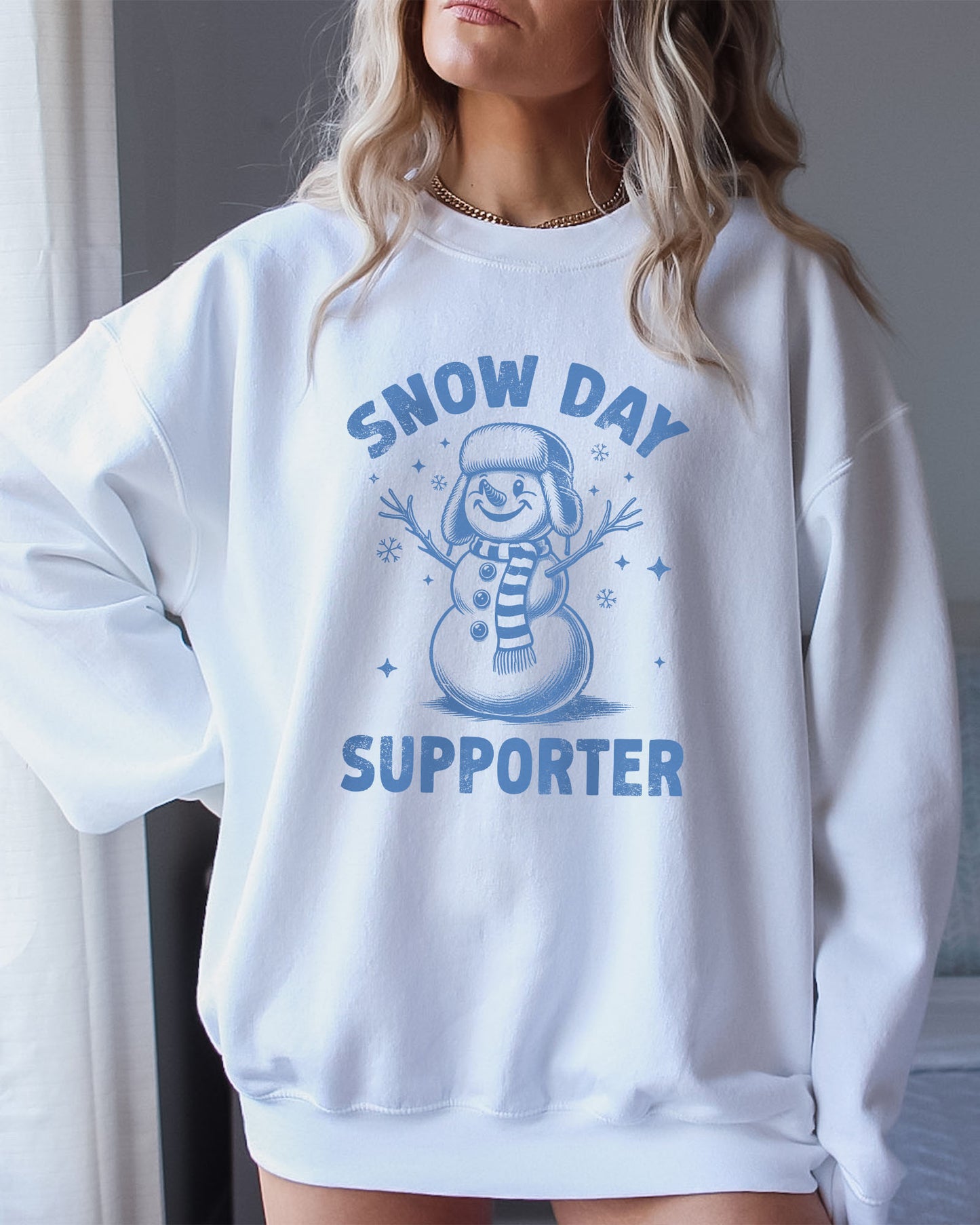 Model wearing white color sweatshirt with 'Snow Day Supporter' graphic design