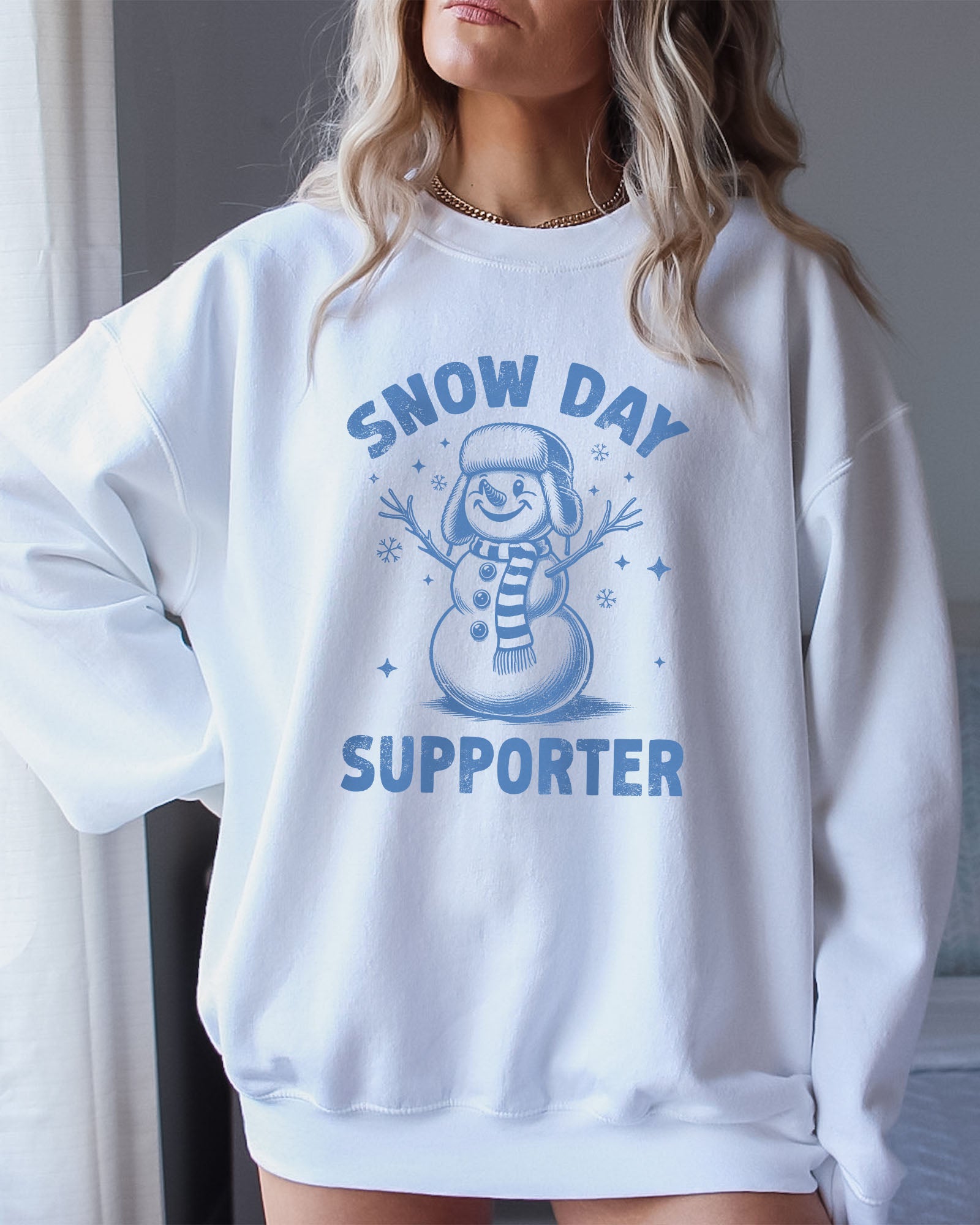 Model wearing white color sweatshirt with 'Snow Day Supporter' graphic design