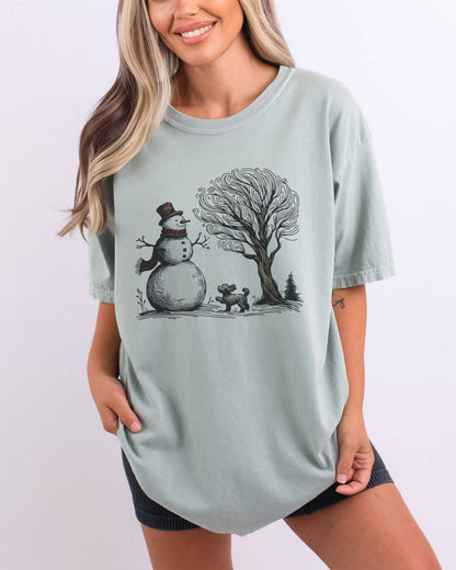 Model wearing bay color shirt with snowman and og winter landscape graphic design