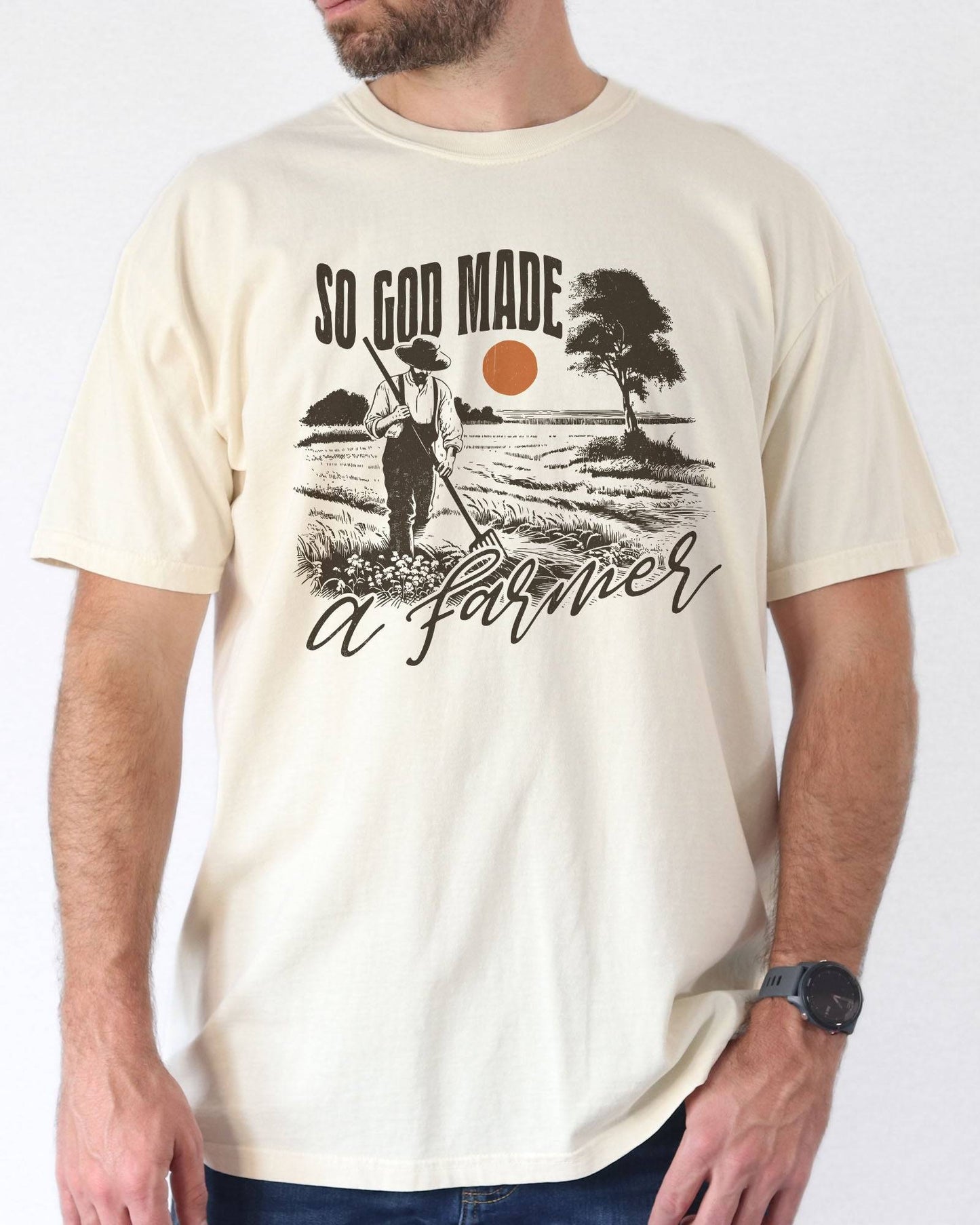 Model wearing ivory color shirt with 'So God Made A Farmer' graphic design