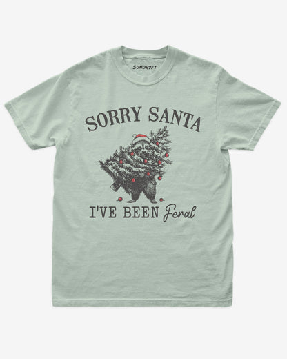 Sorry Santa I've Been Feral shirt in bay with raccoon eating Christmas tree graphic