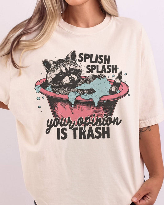 Close-up of "Splish Splash Your Opinion is Trash" shirt in ivory color with funny raccoon in bathtub graphic.