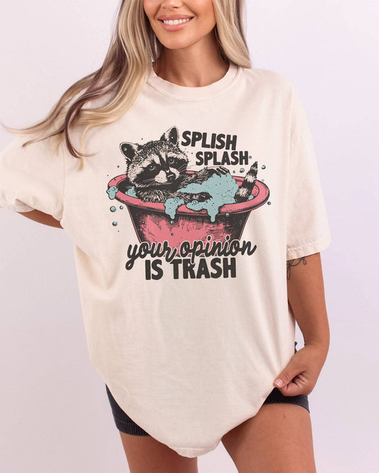 Woman wearing "Splish Splash Your Opinion is Trash" shirt in ivory color with funny raccoon in bathtub graphic.