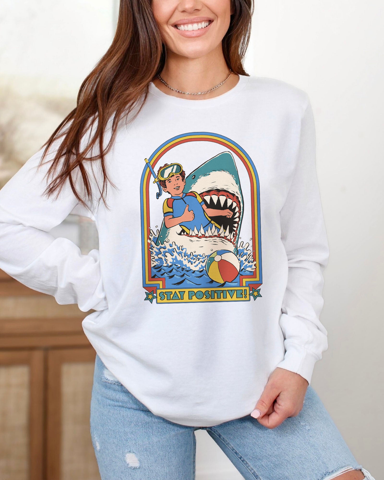 Model wearing white color long sleeve tee with 'Stay Positive Shark' graphic design