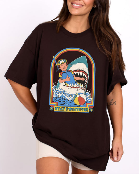 Model wearing dark chocolate color shirt with 'Stay Positive' diver in sharks mouth graphic design