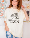 Model wearing ivory color shirt with 'Stay Rowdy' cowgirl walking alligator graphic design