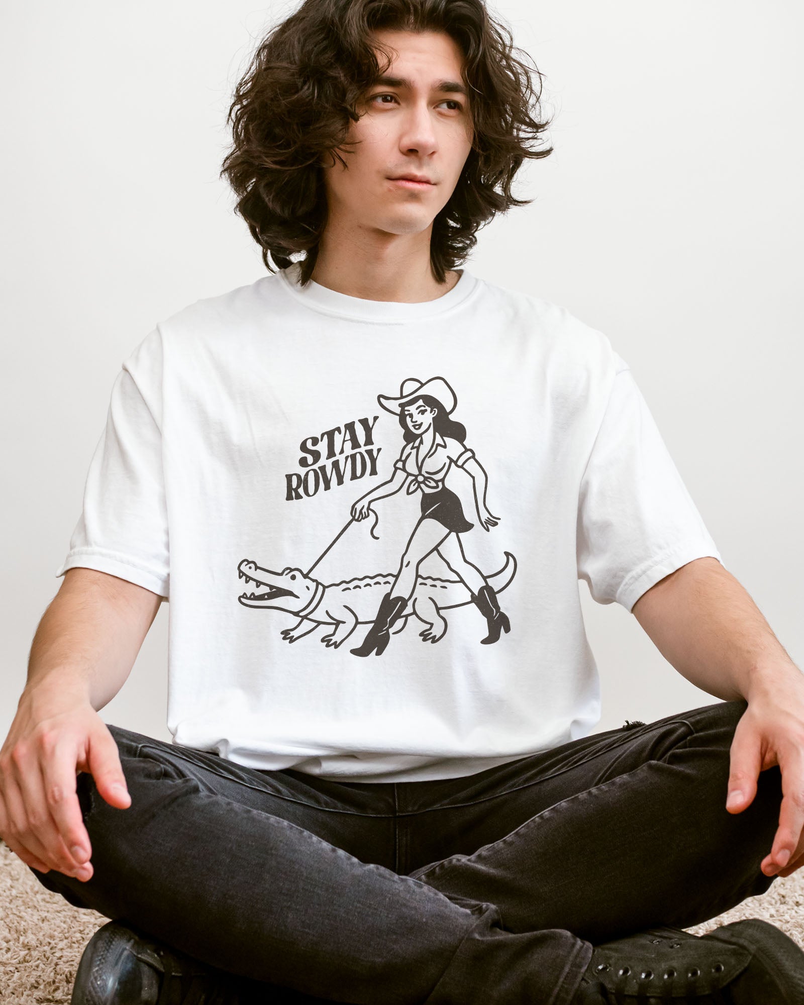 Model wearing white color shirt with 'Stay Rowdy' cowgirl walking alligator graphic design