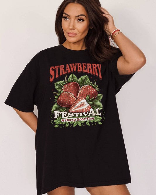 Woman wearing "Strawberry Festival - A Berry Good Time" shirt in black color with a retro strawberries collage graphic.