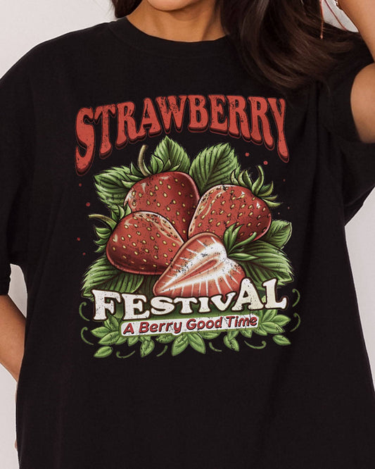 Close-up of woman wearing "Strawberry Festival - A Berry Good Time" shirt in black color with a retro strawberries collage graphic.