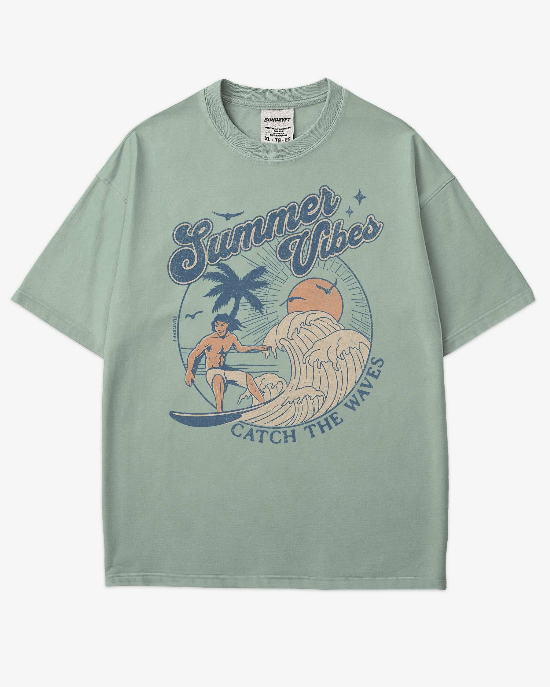 Flat lay bay 'Summer Vibes – Catch the Waves' surf shirt with a retro graphic of a surfer riding a wave on the beach.