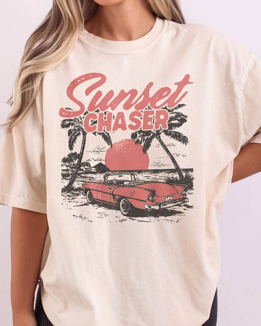 Close-up of ivory shirt with the quote "Sunset Chaser" and a retro car on a beach scenery graphic.