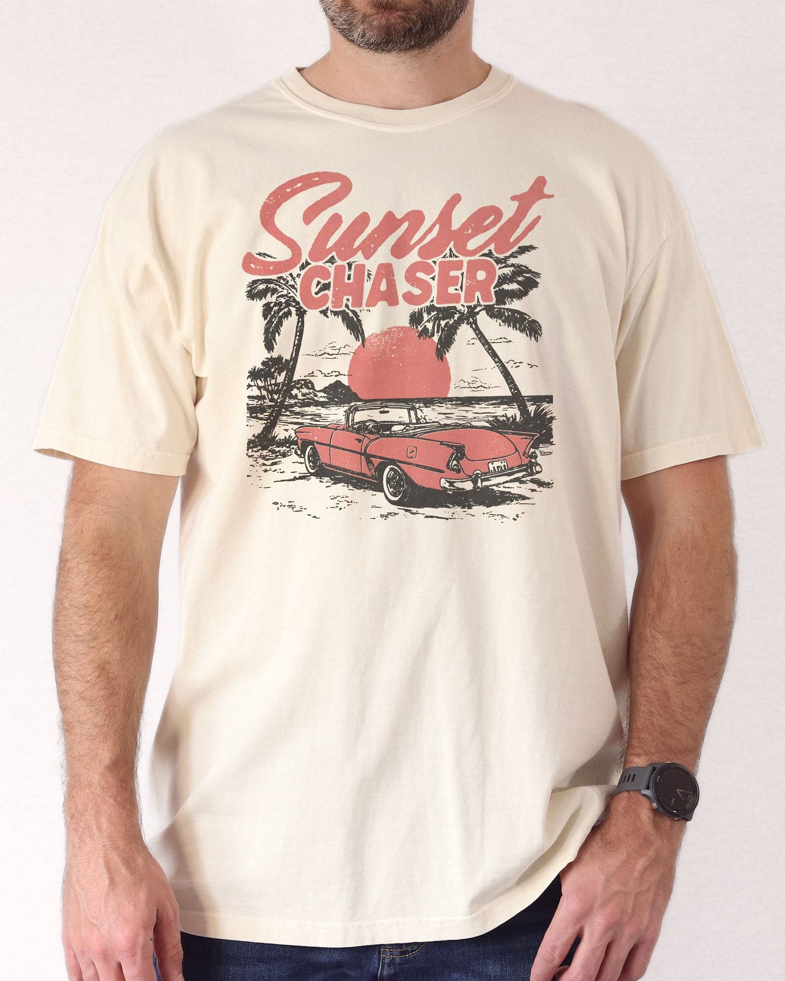 Man wearing ivory shirt with the quote "Sunset Chaser" and a retro car on a beach scenery graphic.
