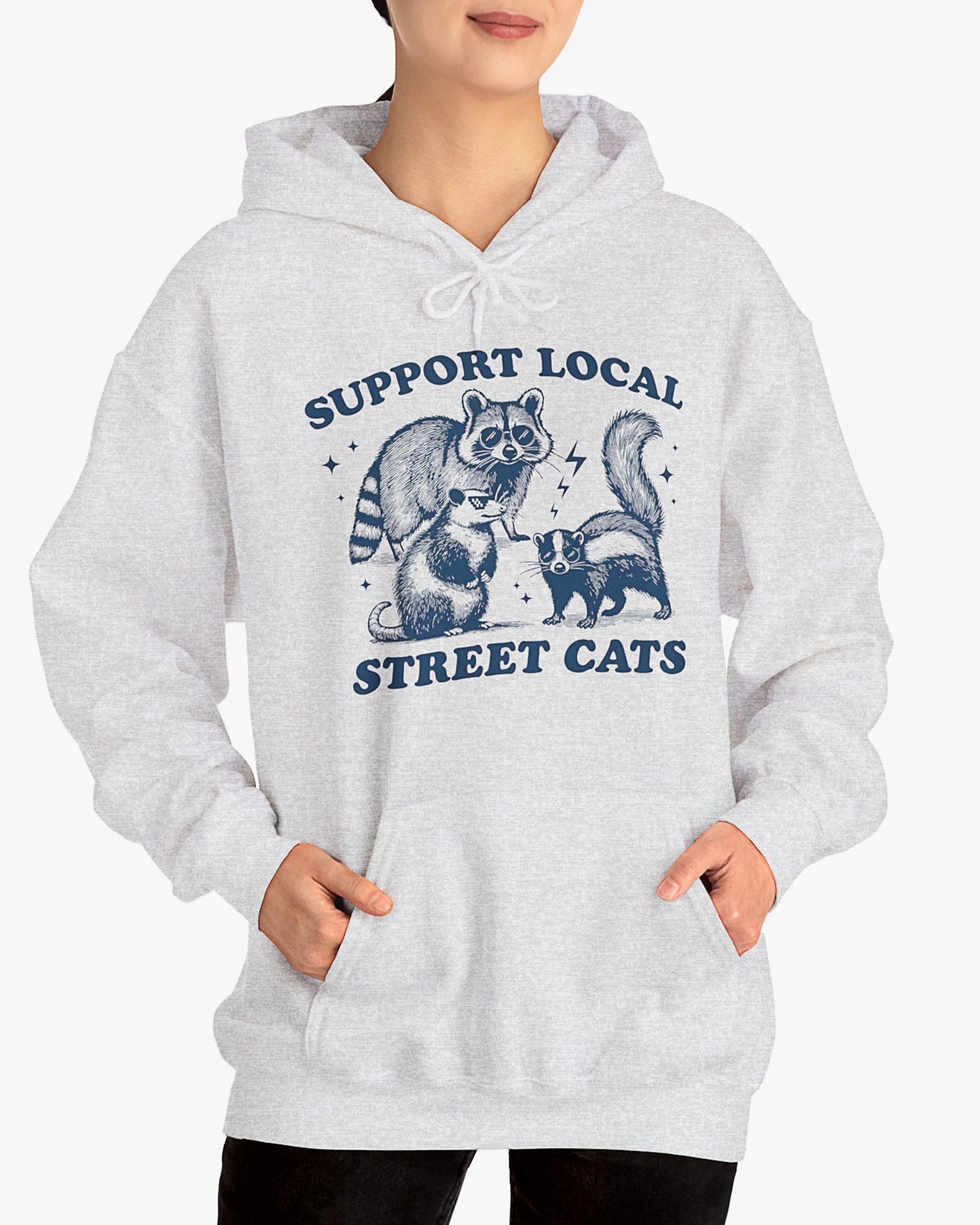 Woman wearing ash gray 'Support Local Street Cats' hoodie with a funny raccoon and opossum retro graphic