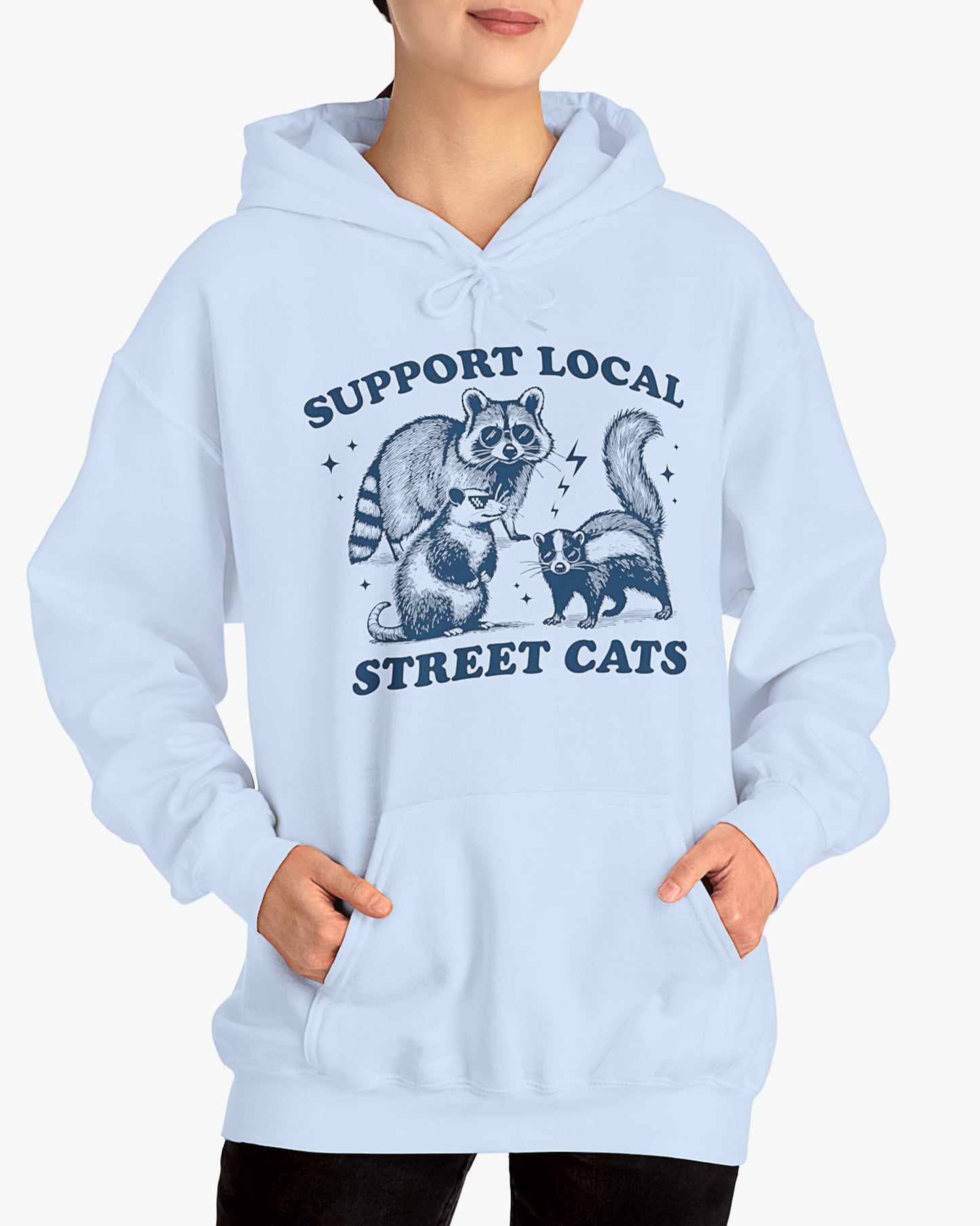 Woman wearing light blue 'Support Local Street Cats' hoodie with a funny raccoon and opossum retro graphic