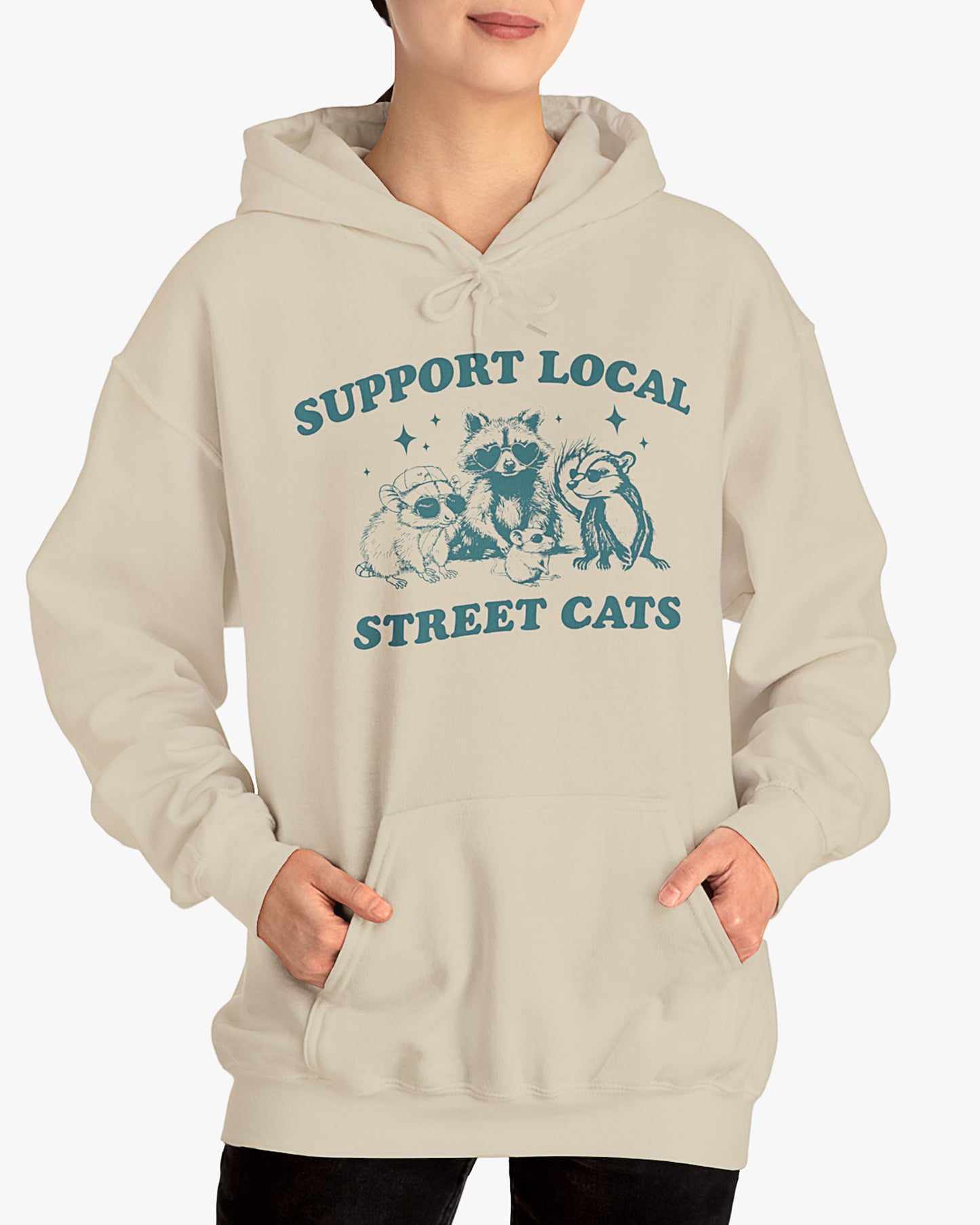 Woman wearing sand beige 'Support Local Street Cats' hoodie with funny retro raccoon and opossum graphic