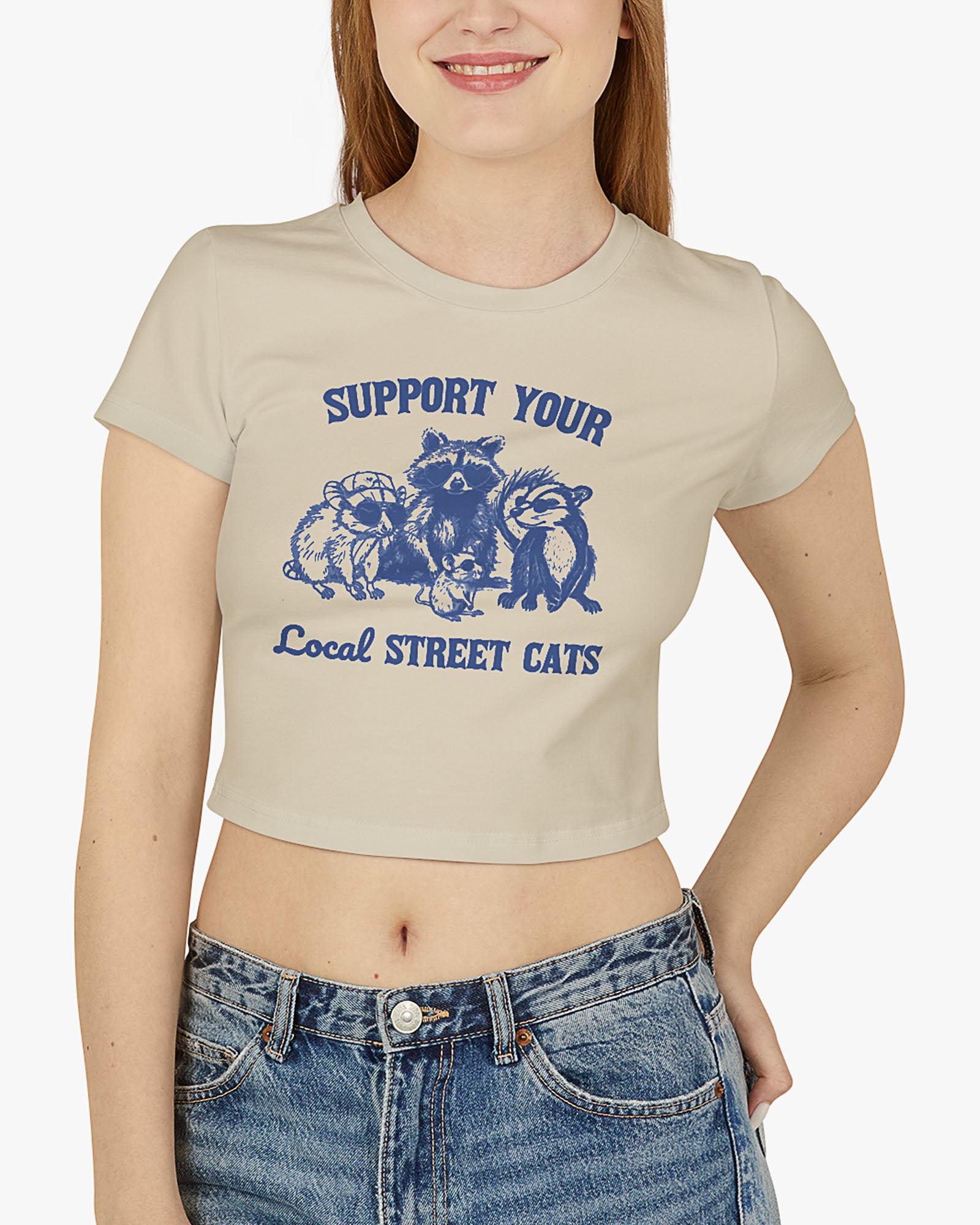 Woman wearing sand beige 'Support Your Local Street Cats' baby tee with funny retro racccoon and opossum graphic
