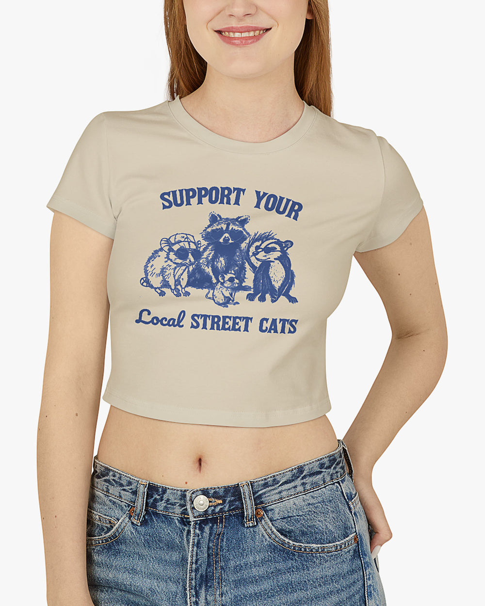 Woman wearing sand beige 'Support Your Local Street Cats' baby tee with funny retro racccoon and opossum graphic
