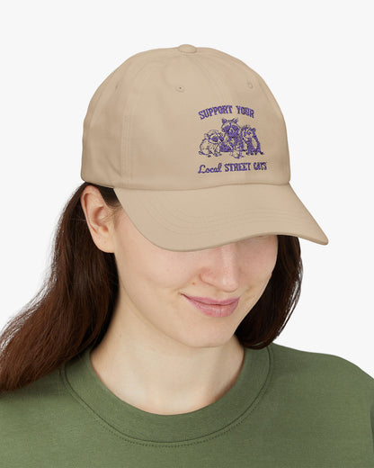 Woman wearing beige dad cap with the quote 'Support Your Local Street Cats' and a funny retro raccoon and opossum graphic.