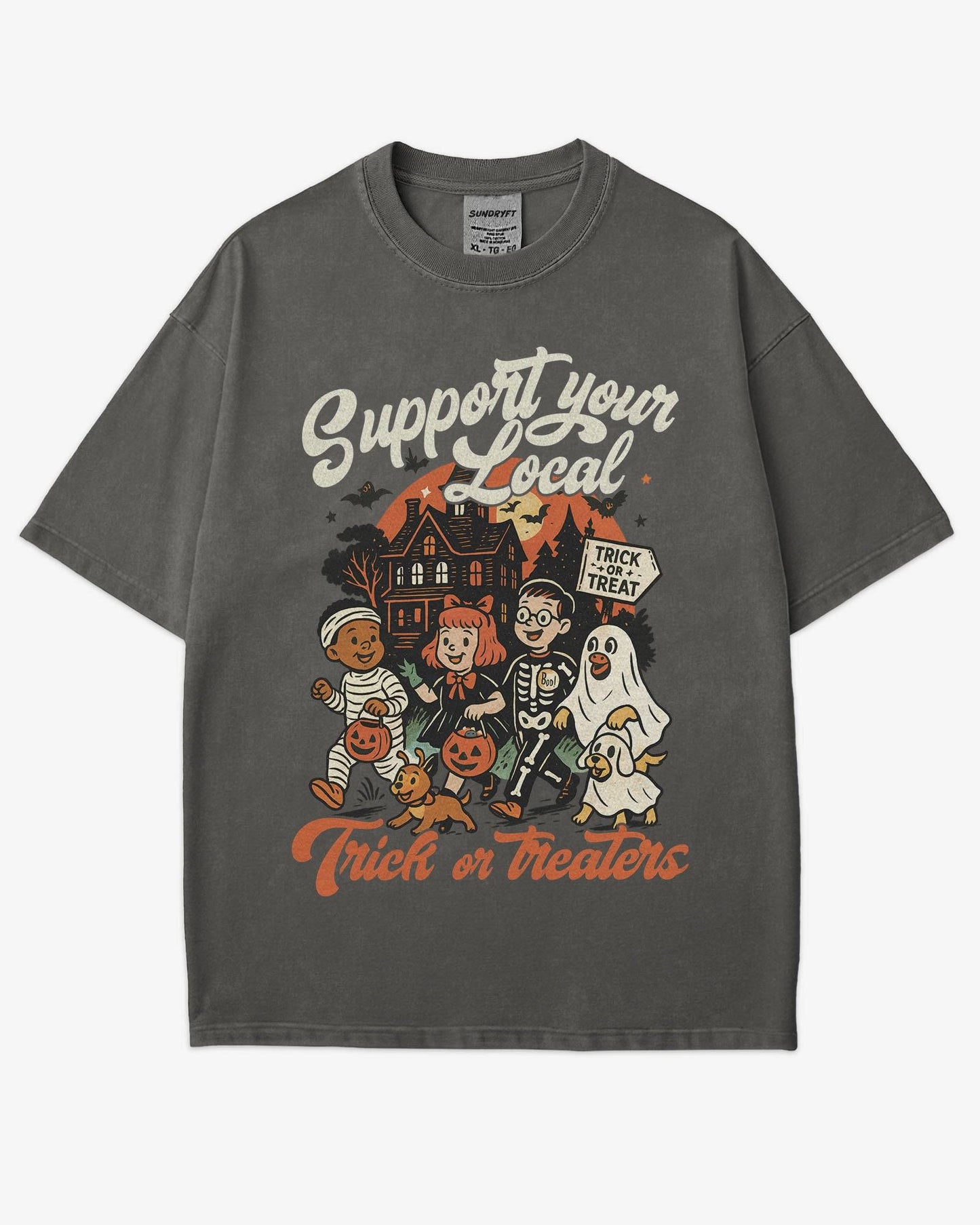 Flat lay pepper ‘Support Your Local Trick Or Treaters’ shirt with retro Halloween graphic of kids trick-or-treating near a haunted house.