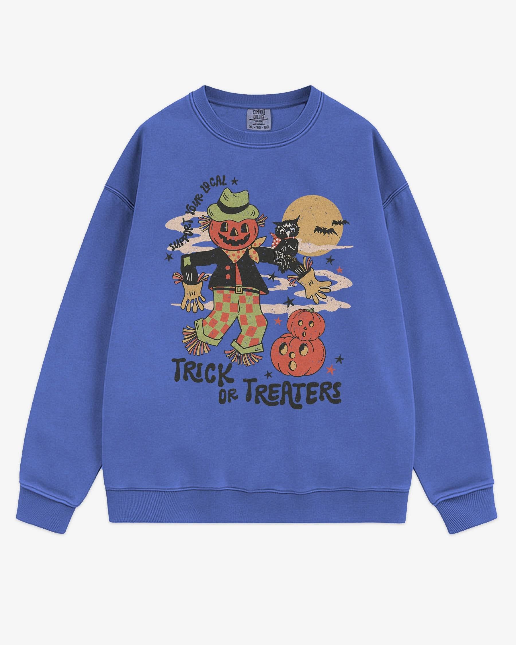 Flat lay flo blue Halloween sweatshirt reading ‘Support Your Local Trick Or Treaters’ with retro graphic of scarecrow, owl, and pumpkins.