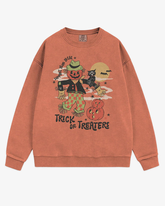 Flat lay terracotta Halloween sweatshirt reading ‘Support Your Local Trick Or Treaters’ with retro graphic of scarecrow, owl, and pumpkins.