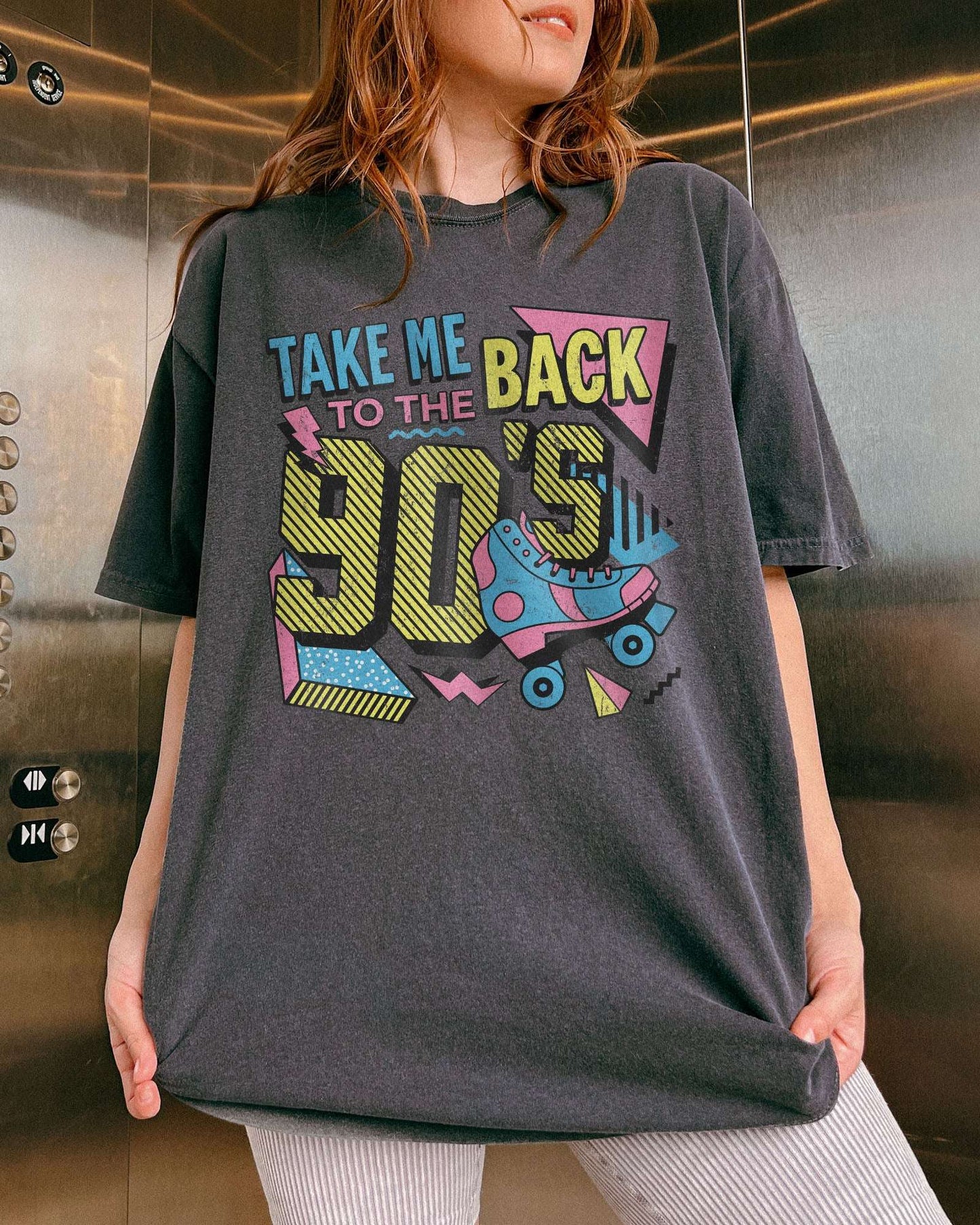 Woman wearing a pepper-colored "Take Me Back To The 90's" retro graphic shirt.