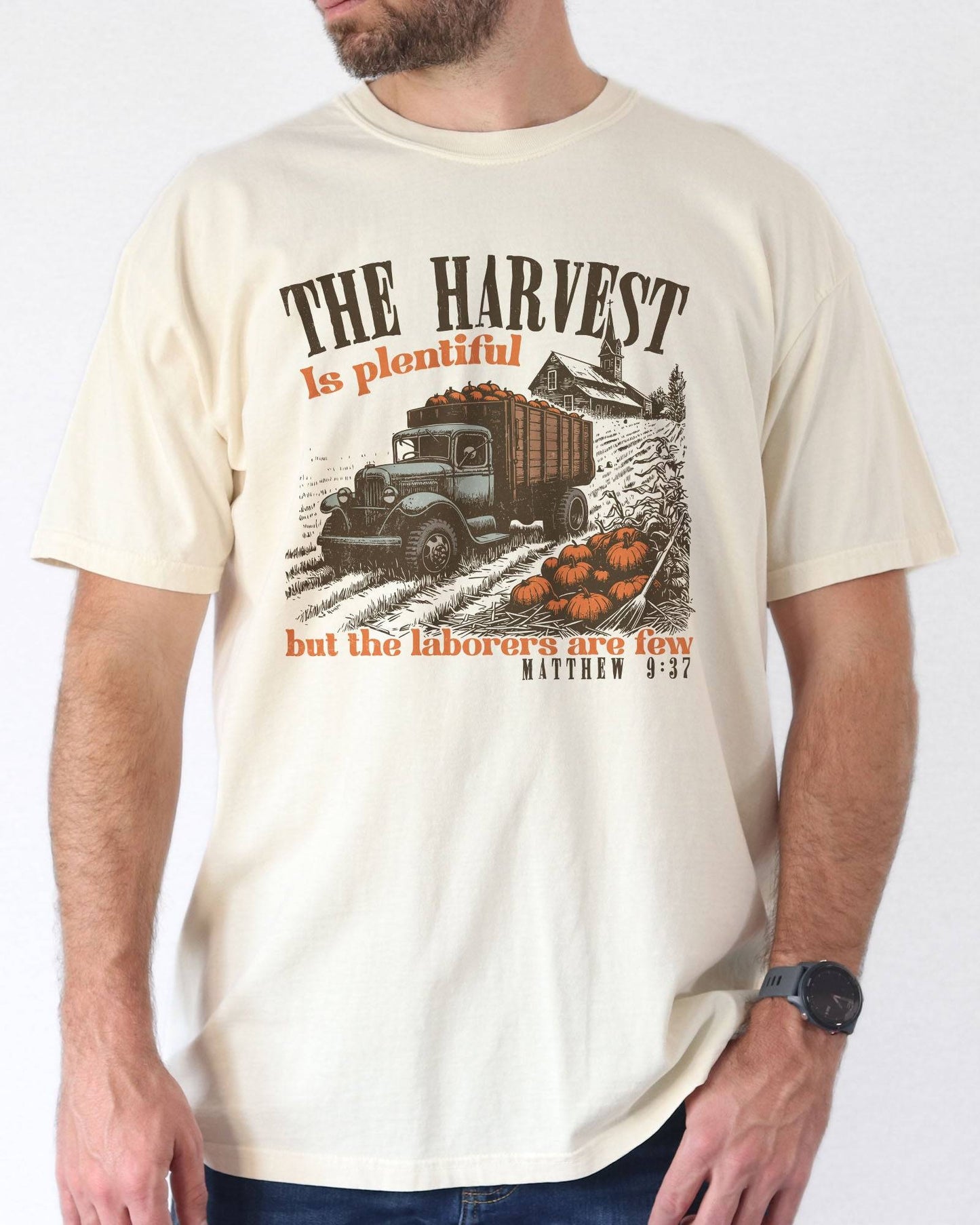 Man is wearing ivory color shirt with 'The Harvest Is Plentiful, But The Laborers Are Few - Matthew 9:37' Thanksgiving graphic design