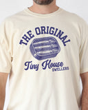 Close-up of a man wearing an ivory "The Original Tiny House Dwellers" shirt featuring a retro graphic of sardines packed in a tin can.