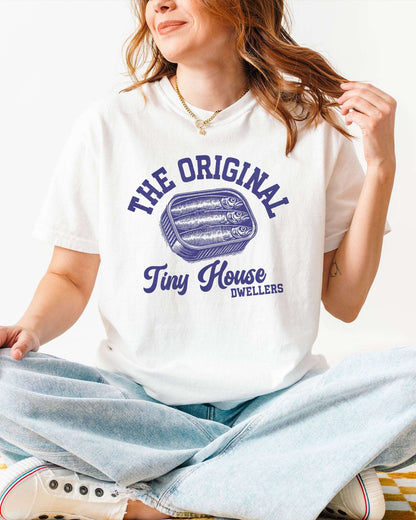 Woman wearing a white"The Original Tiny House Dwellers" shirt featuring a retro graphic of sardines packed in a tin can.