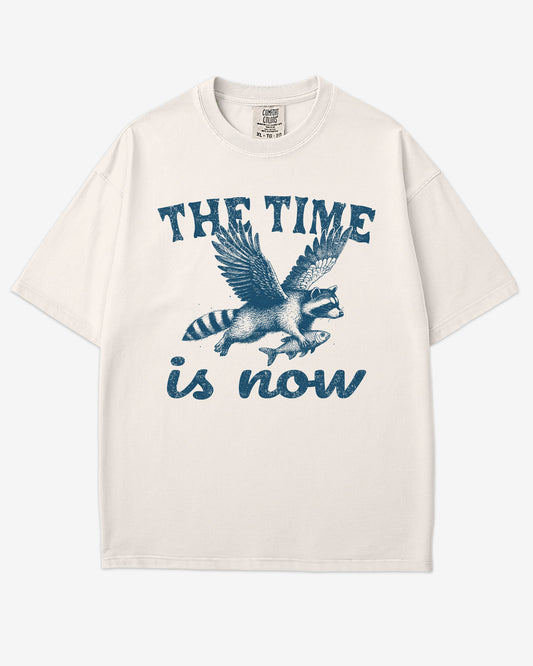 The Time Is Now Shirt flat lay unisex ivory retro tee with funny flying raccoon graphic
