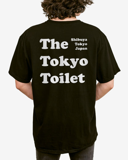 Man wearing a black T-shirt with 'The Tokyo Toilet' text printed on the back, inspired by Shibuya's public toilets.