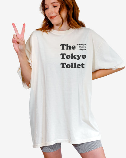 Woman wearing an ivory 'The Tokyo Toilet' shirt, inspired by Shibuya's public toilets.