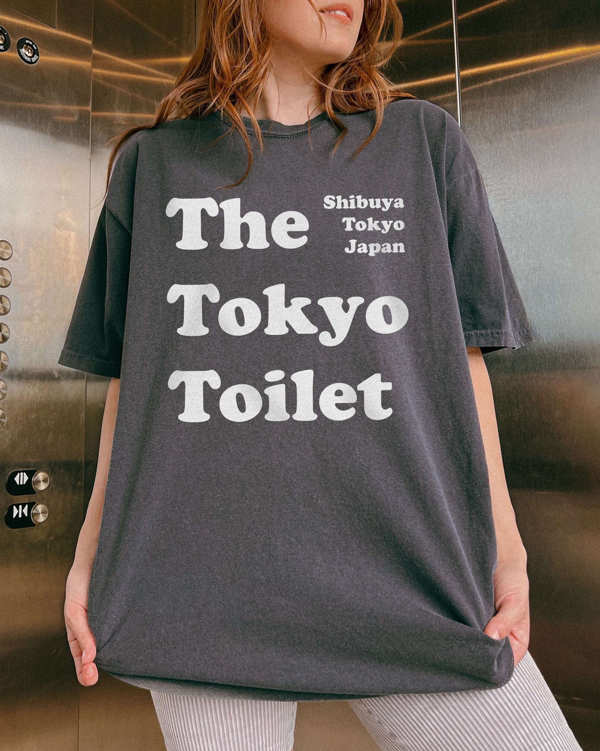 Woman wearing a pepper Tokyo Toilet shirt with a retro graphic inspired by Shibuya’s public restrooms.