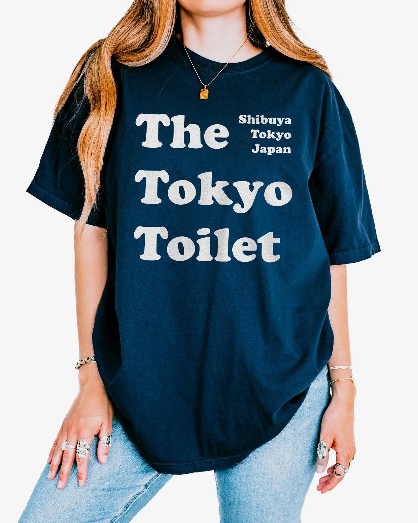 Woman wearing a true navy Tokyo Toilet shirt with a retro graphic inspired by Shibuya’s public restrooms.