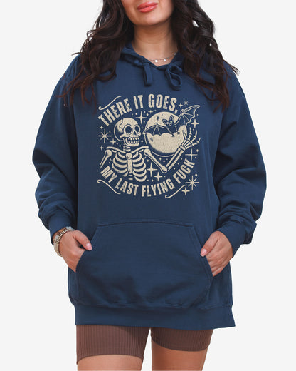 Woman wearing true navy 'There It Goes My Last Flying Fuck' hoodie with funny retro skeleton and bat Halloween graphic.