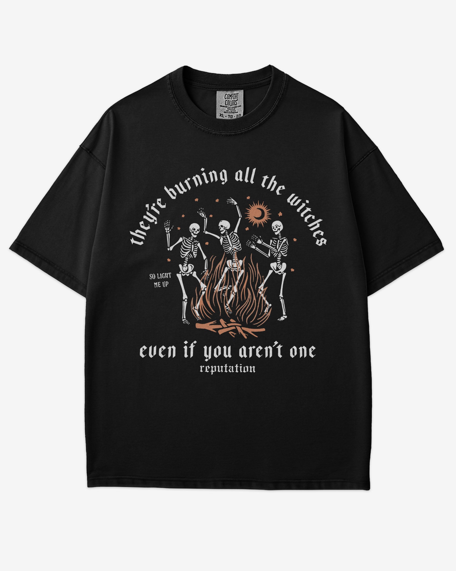They’re Burning All The Witches Shirt – flat lay black tee with funny retro skeletons dancing in fire graphic