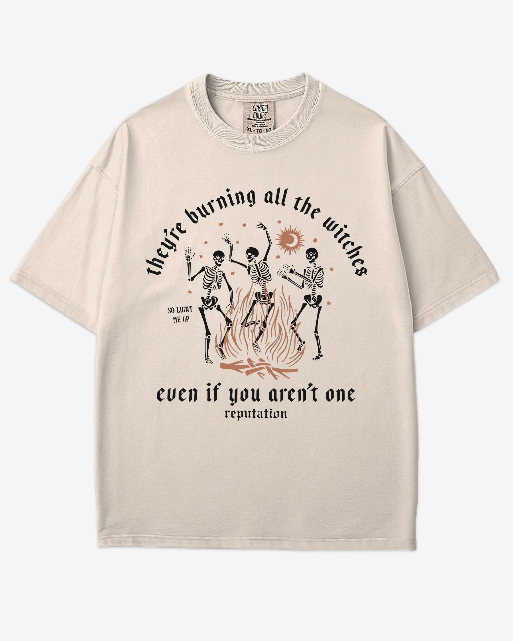 They’re Burning All The Witches Shirt – flat lay ivory tee with funny retro skeletons dancing in fire graphic
