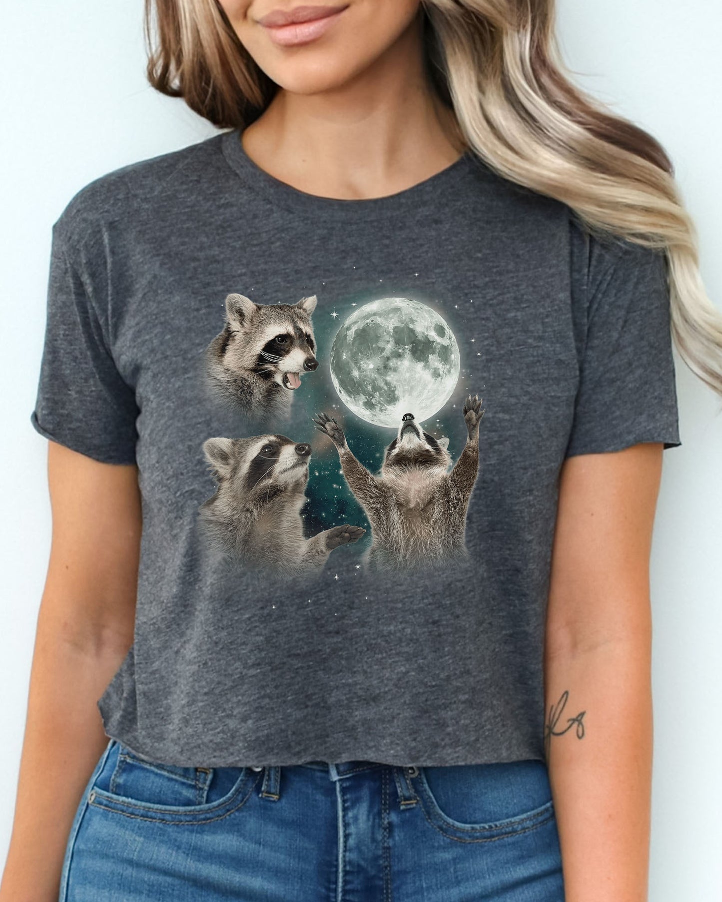 Charcoal gray crop top with a retro graphic of three raccoons howling at the moon, worn by a woman.