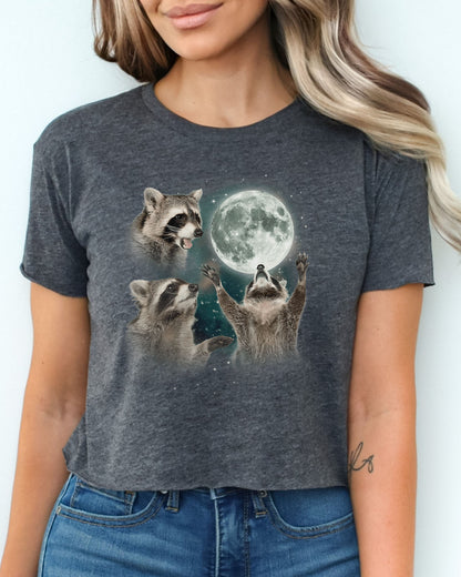 Charcoal gray crop top with a retro graphic of three raccoons howling at the moon, worn by a woman.
